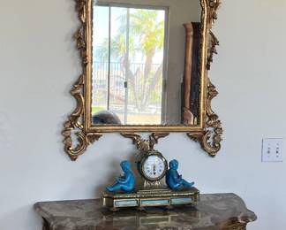 There are three different items in this photo: the mirror, the Sèvres-style French clock, and the wall table.