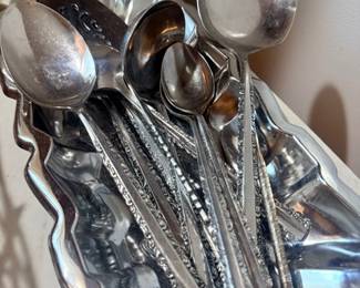 Silver-plated serving spoons in scalloped dish