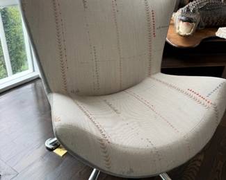 Cream upholstered swivel chair with red saddle stitching