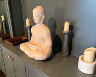 Carved stone Buddha statue with candlesticks