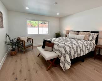 Queen size bed, bedding, throw pillows, accent chair, bench, nightstand, plants