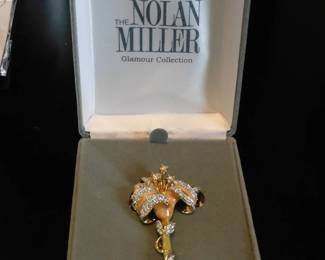 Nolan Miller Glamour Collection lily flower brooch featuring cream enamel and clear crystals set in gold-tone metal.