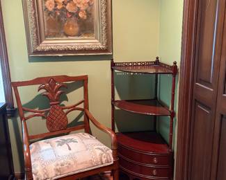 Vintage 1990's Mahogany armchair featuring distinct carved pineapple on backrest and palm tree design on seat. Mahogany corner whatnot shelf features 3 tiers of shelves and 2 bottom drawer. Fretwork on top.