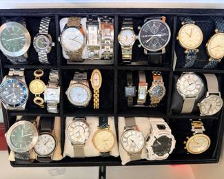 Several Fossil watches (including the black chronograph and some women's models). One white G-Shock. Multiple fashion-brand watches with mesh bracelets.