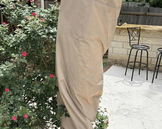 Lot 140: Beige folded patio umbrella with blue interior canopy on round base