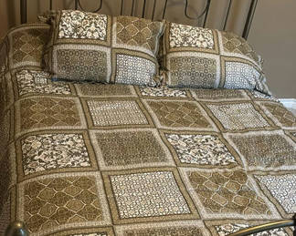 Lot 18: Ornate metal bed frame with quilted bedding