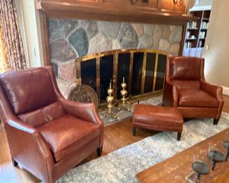 Matched set of "whiskey" leather chairs by Arhaus with an ottoman, and show with ivory and grey 10 x 13 area rug, brass andirons, and vintage brass plate 