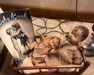 Very old dolls in cradle and book.