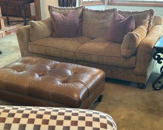 Couch with decorative fringe pillows, and a leather ottoman