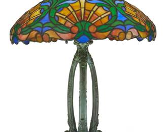 1203 A Duffner & Kimberly 'Art Nouveau' slag glass lamp Early 20th century Numbered in the casting at underside: 318 The shade depicting shells and foliate motifs, mounted on a verdigris patinated bronze base issuing three Harvey Hubbell light fixtures with acorn chain pulls, electrified Shade: 7.25" H x 19.25" Dia.; Base: 20.75" H x 9" W x 8.75" D; Overall: 22" H x 19.25" Dia. Estimate: $8,000 - $12,000