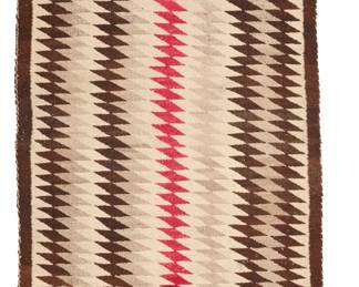 1081 A Navajo regional rug Early 20th century, Diné Woven in red, dark brown, cream, and natural grey wool, with eyedazzler motif 80.5" H x 39.5" W Estimate: $300 - $500