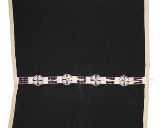 1092 A Plains beaded hide blanket strip on blanket Late 20th century An elaborate polychrome beadwork strip worked in white, blue and red beads with four round shields with hide laces, alternating with geometric blocks, applied to a large black wool blanket with cream wool trim 62" H x 61.5" W approximately Estimate: $600 - $800