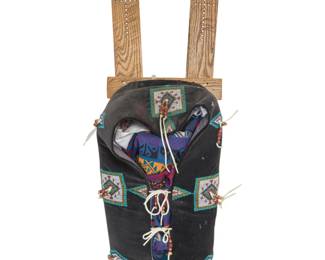 1361 A Plains style beaded cradle Late 20th century With original retailer's tag The lattice boards with brass tacking, the fabric-wrapped hide body adorned with floating geometric beaded elements centered by beaded hide tassels, with conforming lashing 40.75" L x 14.5" W x 11" D Estimate: $300 - $500