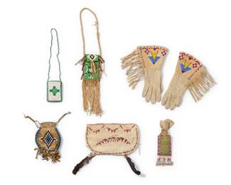 1387 A group of Native American beaded hide items Early 20th century and later Comprising a pair of gloves with beaded geometric elements, and five pouches of various sizes, one adorned with cowrie shell fringe, another mounted with feathers 7 pieces Each glove: 12" L from tip to opening x 3.75" W at wrist; Largest without feathers: 6.5" H x 11" W Estimate: $300 - $500