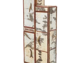 1419 A rustic birch bark cabinet 2002 Incised signature and date verso: C. HUOX Clad in birch bark to fronts and sides, decorated with applied wood heartline and painted hide motifs, the three cabinets with antler pulls, each opening to reveal multiple shelves and painted interior 53.25" H x 21.25" W x 10.5" D Estimate: $200 - $400