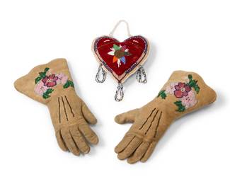 1388 A pair of Northeast beaded hide gloves and whimsy Mid-20th century; Northeast United States/Canada Comprising a pair of gloves adorned with floral motifs, and a beaded heart-shaped whimsy with beaded tassel loop accents 3 pieces Each glove: 11.5" L from tip to opening x 3.5" at wrist; Whimsy: 6" H x 6.125" W x 2" D Estimate: $100 - $200