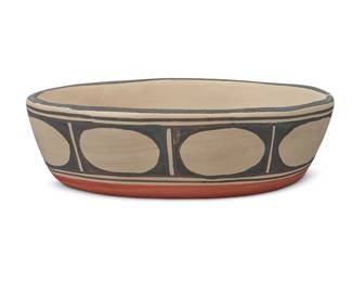 1322 Robert Tenorio (b. 1950, Santo Domingo Pueblo) A polychrome pottery low oval bowl, late 20th/early 21st century Signed to underside: Robert Tenorio / Santo Domingo Pueblo With black geometric motif to interior and banded circles to exterior on white slip, above a terracotta wash 2.875" H x 9.625" W x 6.375" D Estimate: $200 - $400