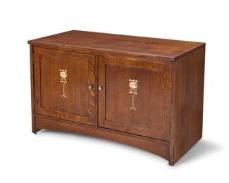 1333 A Stickley Harvey Ellis inlaid console cabinet, no. 89-1192 2013 With factory burn mark and two applied metal labels including Mission Reissue; stamped with date and: 89 1192 / #32; impressed: TT Each door with inlaid accent depicting a landscape scene in a cartouche within ivy designed by Harvey Ellis (1852-1904), opening to reveal three adjustable height shelves, possibly later fitted with power strip and pull-out CD storage racks, the verso with removeable sliding doors 28.5" H x 43.5" W x 22" D Estimate: $600 - $800
