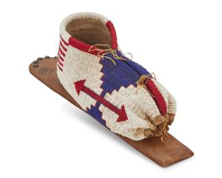 1360 A Plains pictorial beaded hide doll cradle Mid-20th century Beaded burlap with American flag motif, mounted to a wood board with hide strapping, brass tacking, and painted with American flags 18" L x 5" W x 7" D Estimate: $400 - $600