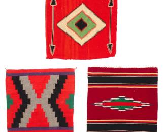 1414 Three Chimayo and Navajo textiles Mid-20th century Each woven in multicolor wool on a red ground, one with a central floating geometric element with opposed banding, another with stepped X-form, and one with central serrated diamond and arrows, converted into a pillowcase with sewn backing 3 pieces Largest: 19.25" H x 18.25" W; Smallest: 18" H x 17.5" W Estimate: $200 - $400