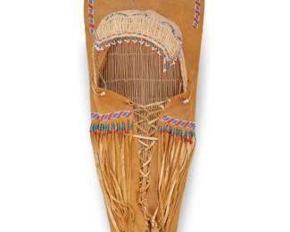1044 A Paiute beaded hide and basketry cradleboard Late 20th century; Great Basin With basketry framework and visor wrapped in hide adorned with beaded accents, with plastic beaded fringe 38.5" L x 14.25" W x 13.25" D Estimate: $300 - $500
