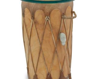 1281 A Native American hide drum as a side table Late 20th century Stretched hide over carved wood, with leather lashing, single handle, beveled glass top, and hide-wrapped beater 3 pieces Drum: 21" H x 13" W x 12" D; Glass: 0.375" H x 14.125" Dia.; Beater: 14.5" L Estimate: $200 - $300