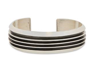 2029 A Tom Hawk Navajo sterling silver cuff bracelet Tom Hawk (b. 20th century, Diné) Late 20th/21st century Stamped: Tom Hawk / Sterling A chunky cuff with deeply incised bands 6.625" total inner C x 0.75" H, gap: 1" 49.0 grams gross Estimate: $200 - $400