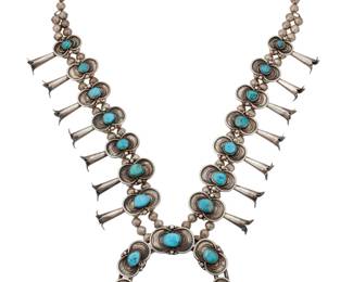 2126 A Southwest sterling silver and turquoise squash blossom necklace Mid-20th century Unmarked A chunky necklace with fourteen graduated shadowset turquoise blossoms, with a large matching two-wire naja, each plaque with silver wire and silver ball accents, and all on a double strand of silver beads 26.5" L x 3.5" H 193.6 grams gross Estimate: $700 - $900