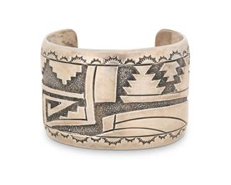 2201 A Norman Woody Navajo sterling silver cuff bracelet Norman Woody (b. 20th century, Diné) Late 20th century Stamped: NW / Sterling A wide cuff with elaborate geometric and stepped diamond motifs in silver overlay, and stampwork edge detail 7" total inner C x 1.875" H, gap 1.5" 100.8 grams gross Estimate: $300 - $500