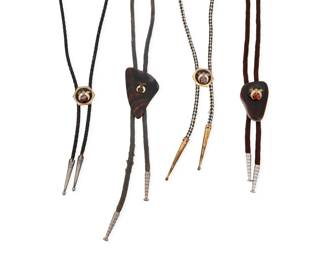 2252 A group of Masonic Western style bolo ties Late 20th century Unmarked Comprising four bolo ties, two with polished brown stone slides and two with mixed metal slides, each with central plaque featuring Freemasonry symbols, two mounted to braided cords and two mounted to fabric cording, each with metal tips 4 pieces Largest bolo slide: 2.5" H x 1.5" W; Smallest: 1" Dia.; cords: 35" L to 33" L approximately 103.6 grams gross Estimate: $200 - $300