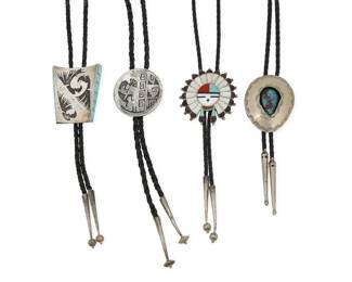2248 A group of Southwest silver bolo ties Mid/late 20th century Two variously marked for unknown makers: JK / NPL Four works comprising a large Zuni-style Sunface sterling silver bolo with multistone coral, turquoise and mother of pearl inlay, a large Hopi-style trapezoidal sterling silver overlay bolo with stylized geometric avian motifs and turquoise inlay to sides, as well as a round sterling silver overlay bolo with Kokopelli and geometric motifs, and an oval shadowbox set turquoise silver mixed metal bolo, each bolo suspended from a braided black leather cord with silver cone tips of various designs 4 pieces Largest bolo slide: 2.375" H x 2.125" W ; Smallest: 2" Dia.; cords: 48" L to 36" L approximately 185.2 grams gross Estimate: $500 - $700