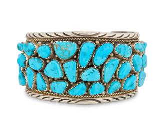 2018 An Elain Bahe Navajo sterling silver and cluster set turquoise cuff bracelet Elain Bahe (b. 20th century, Diné) Late 20th century Etched signature: E. Bahe A heavy shaped tapered cuff with multiple cluster set turquoise stones of various shapes, and with deeply stamped edges 7.25" total inner C x 1.75" H, gap: 1.625" 116.4 grams gross Estimate: $300 - $500