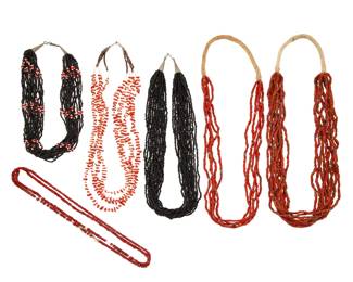 2214 A group of Pueblo shell and trade bead necklaces Mid/late 20th century Unmarked Comprising two multistrand red bead necklaces, one with ten strands (28.5" L) and one with five strands and silver beads (29" L), each with a traditional wrapped neck cord, together with a four-strand necklace with coral and heishi shell beads and silver cone clasps (25" L), two multistrand necklaces of black beads (26" L & 20" L), and two single strands of red and white glass "white heart" trade beads (23" L & 22" L) 7 pieces 559.1 grams gross Estimate: $500 - $700