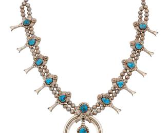 2131 A Southwest sterling silver and turquoise squash blossom necklace Mid/late 20th century Stamped: Sterling A double strand necklace with ten ornate set turquoise blossoms with silver feather and floral overlay motifs, suspending a matching two-wire set stone naja with central blossom dangle 26.75" L x 3" H 119.4 grams gross Estimate: $500 - $700