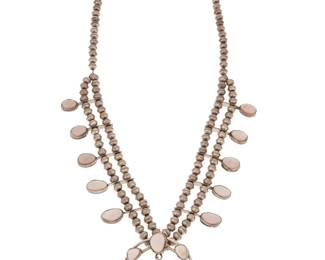 2135 A Southwest sterling silver and mother of pearl squash blossom necklace Mid-20th century Unmarked A delicate necklace with ten graduated blossoms and a matching central naja, all suspended from a double strand of silver beads 25" L x 2.25" H 87.7 grams gross Estimate: $600 - $800