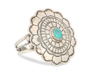 2240 A Southwest sterling silver and turquoise concho cuff bracelet Late 20th century Stamped: Buffalo Dancer [for Taos, NM shop] / Sterling A three wire cuff with a large stamped round concho with set turquoise cabochon 6.25" total inner C x 2.375" H, gap: 1" 48.5 grams gross Estimate: $400 - $600