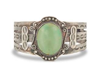 2027 A Southwest sterling silver Fred Harvey style cuff bracelet Early/mid-20th century Stamped: Sterling The openwork cuff with a central set green stone and extensive stampwork and silver wire and ball accents 6.75" total inner C x 1.5" H, gap: 1" 41.7 grams gross Estimate: $200 - $400