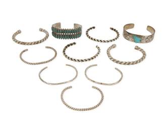 2310 A group of Southwest style silver cuff bracelets Mid/late 20th century Zuni cuff marked for sterling Ten works comprising a Fred Harvey-style stamped and applied silver cuff with set carved turquoise arrowhead, a Zuni-style two-wire row set petit point turquoise cuff with stamped terminals, two narrow ridged wire cuffs with stampwork, and three pairs of twisted wire cuffs in various gauges 10 pieces Largest: 6.75" total inner C x 0.75" H, gap: 1"; Smallest: 6.25" total inner C x 0.125" H, gap: 1.125" 201.5 grams gross Estimate: $300 - $500