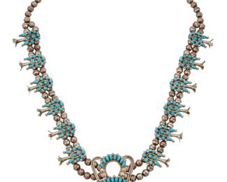 2068 A Viola & Jacob Bobelu Zuni silver and turquoise squash blossom necklace Viola and Jacob Bobelu (each b. 20th century, Zuni Pueblo) Late 20th century Etched: Vie & Jacob Bobelu / Zuni A delicate double strand necklace with twelve cluster set turquoise blossoms, suspending a large cluster set sterling silver naja with silver rope wire accents, and tapered silver cone terminals 29" L x 3" H 116.6 grams gross Estimate: $700 - $900