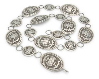 2107 A Gibson Gene Navajo sterling silver link concho belt Gibson Gene (b. 20th century, Diné) Mid/late 20th century Stamped to buckle: [bird picto] / Sterling A silver link belt featuring oval conchos and a buckle, alternating with round spacers, each in Hopi-style silver overlay in katsina mask designs 37.75" L x 1.5" H (buckle); ach oval concho: 1.5" H x 2.25" W; spacer: 1.125" Dia. 155.8 grams Estimate: $500 - $700