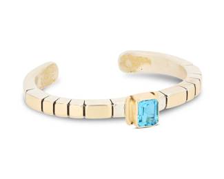 2038 A Julian Nez Navajo sterling silver and 14K gold gem-set cuff bracelet Julian Nez (b. 20th century, Diné) Late 20th century Stamped: J. Nez [script] / 14K / Sterling A narrow modernist style angled sterling cuff with incised banding details and central 14k gold set synthetic blue quartz gemstone 6.125" total inner C x 0.375" H, gap: 1" 44.7 grams gross Estimate: $500 - $700