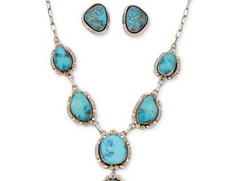 2109 A mixed set of Esther Wood Navajo sterling silver and turquoise jewelry Esther Wood (b. 1946, Diné) Late 20th/21st century Each with etched signature verso A large set turquoise link necklace with detachable drop pendant, each link with heavily stamped edging, all suspended by paperclip chains, with a pair of similar shadowbox set turquoise earrings 3 pieces 22.75" L x 3.25" H; Earrings: 1.5" H 175.9 grams gross Estimate: $800 - $1,200