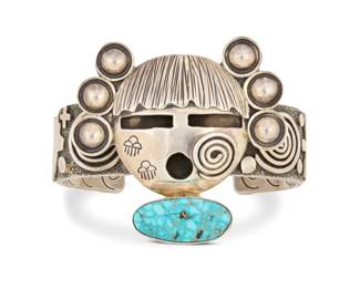 2001 An Alex Sanchez Navajo sterling silver and turquoise cuff bracelet Alex Sanchez (b. 1967, Diné/Zuni) 21st century Stamped for artist and for sterling A chunky cuff featuring a central sculptural Katsina mask and set turquoise, with applied silver petroglyph and bear motifs to band and stampwork to interior 6.5" total inner C x 2" H, gap: 1.25" 102.8 grams gross Estimate: $700 - $800