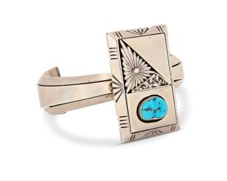 2273 A Delbert Vandever Navajo sterling silver and turquoise cuff bracelet Delbert Vandever (b. 20th century, Diné) Late 20th/21st century Stamped: Delbert Vandever / Sterling A modernist style tapered cuff with central rectangular plaque with geometric applied silver and overlay, with set turquoise and stamped edges 6" total inner C x 1.75" H, gap: 1.125" 58.7 grams gross Estimate: $400 - $600