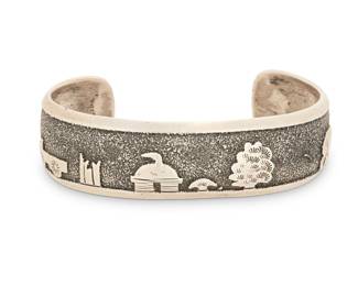 2053 A Tommy Singer Navajo sterling silver Storyteller cuff bracelet Thomas 'Tommy' Singer (1940-2014, Diné) Late 20th/21st century Stamped: Thomas Singer / Sterling A chunky cuff with silver overlay Navajo hogan and landscape scene with trees and a wagon 7" total inner C x 0.75" H, gap: 1.375" 23.9 grams Estimate: $400 - $600