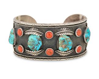2017 A Southwest sterling silver, turquoise and coral cuff bracelet Mid/late 20th century Unmarked A large heavy cuff with row set nugget turquoise and coral cabochons, with applied silver feather accents and stamped edges 7.75" total inner C x1.5" H, gap: 1" 100.4 grams gross Estimate: $500 - $700