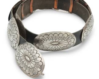 2104 A Southwest sterling silver concho belt Mid/late 20th century Stamped: SM [possibly Sheryl Martinez, Navajo/Diné] / Sterling Comprising nine oval domed conchos and matching buckle, each with elaborate stampwork detail, and all mounted to a black leather belt strap Buckle and each concho: 1.5" H x 2.75" W; Belt: 32" L x 1" H 202.4 grams gross Estimate: $500 - $700