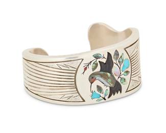 2064 A Jake & Irene Livingston Navajo sterling silver and multistone inlay cuff bracelet Jacob [Jake] & Irene [Owens] Livingston (b. 1946, Diné/Zuni and b. c. 1950, Diné) Late 20th/ 21st century Stamped: J - I Livingston / Sterling A chunky silver asymmetrical shaped tapered cuff with hummingbird and foliate motif in turquoise, carved stone, and shell inlay, with deep incised banding to shoulders 6.5 total inner C x 1.25" H, gap: 1" 106.7 grams gross Estimate: $400 - $600