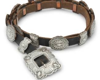 2105 A Southwest sterling silver concho belt Late 20th century Stamped: D / Sterling Comprising a rectangular buckle with nine small oval conchos and ten butterfly spacers, each with stampwork and overlay designs and all mounted to a leather belt strap Buckle: 2.125" H x 2.625" W; Each concho: 1.25" H x 1.5" W; spacer: 1.25" H x 0.75" W ; Belt: 39.5" L x 0.75" H 253.0 grams gross Estimate: $400 - $600