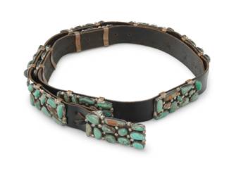 2097 A Southwest sterling silver and turquoise concho belt Mid-20th century Stamped: E.A. / Sterling A narrow belt with nine cluster set turquoise rectangular conchos and a matching buckle, all set to a black leather belt strap Buckle and each concho: 1" H x 2.25" W; Belt: 36" L x 1" H 276.6 grams gross Estimate: $1,000 - $1,500